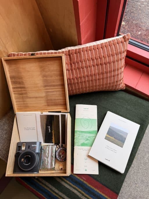 The open wooden analogue kit with a film camera, printed booklets and an old Nokia phone.