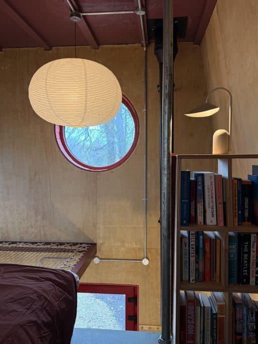 The reading loft with a paper lantern, a bookshelf and the porthole window.
