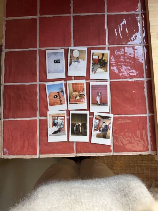 Polaroid photographs from a stay, laid out on the red tiles.