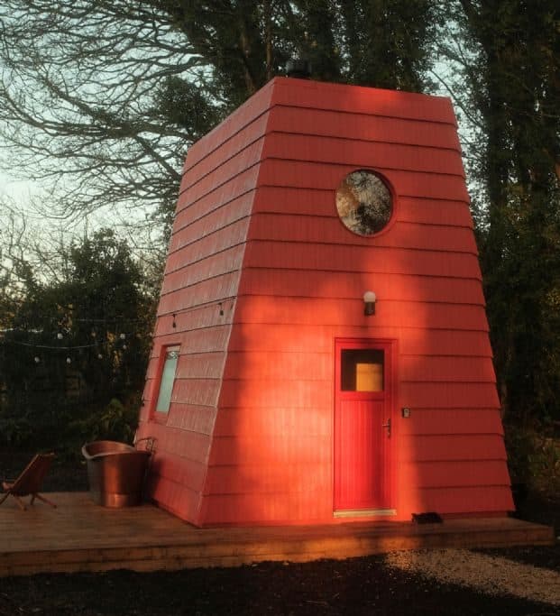 Cucu at dusk, its red shingles glowing and a single round window near the roof.